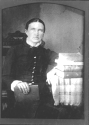 Susan sitting at a table covered with a cotton large-checked cloth, and a stack of books