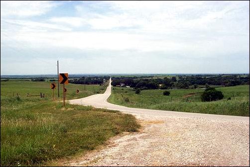 Yellow gravel road stretching in curves to the horizon