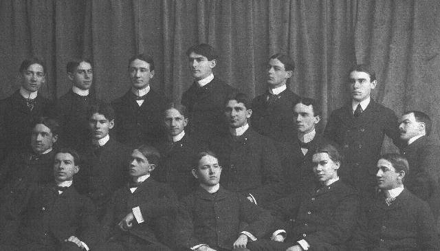 Close-in photograph taken with fraternity sitting in three rows, each higher than the other; they are looking in various directions, and appear very casual
