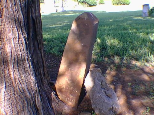 Red stone leaning away from the base of a tree; lettering says J Z I WATTS SEP 21 18??
